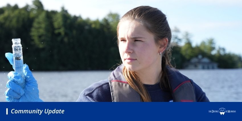 Girl looking at a test tube while sitting in a boat on a lake. 